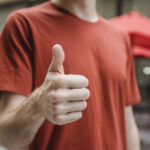 Unrecognizable man showing thumb up on city street